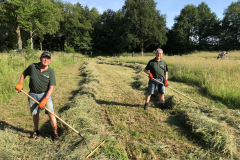 Gerrit en Bert harken het maaisel op kidden 